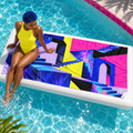 Woman seated beside Level Unlocked beach towel at a pool.