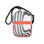 Rear view of the Wrong Turn crossbody bag with black-and-white curved stripes and an orange band.