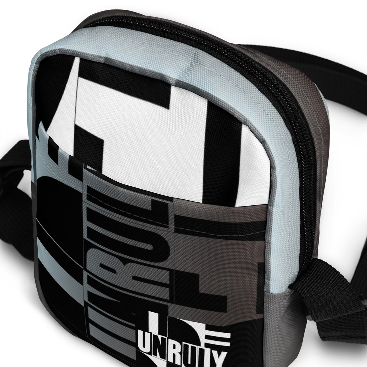 Close-up of the Unruly bag's front pocket, geometric typography, and black top zipper.