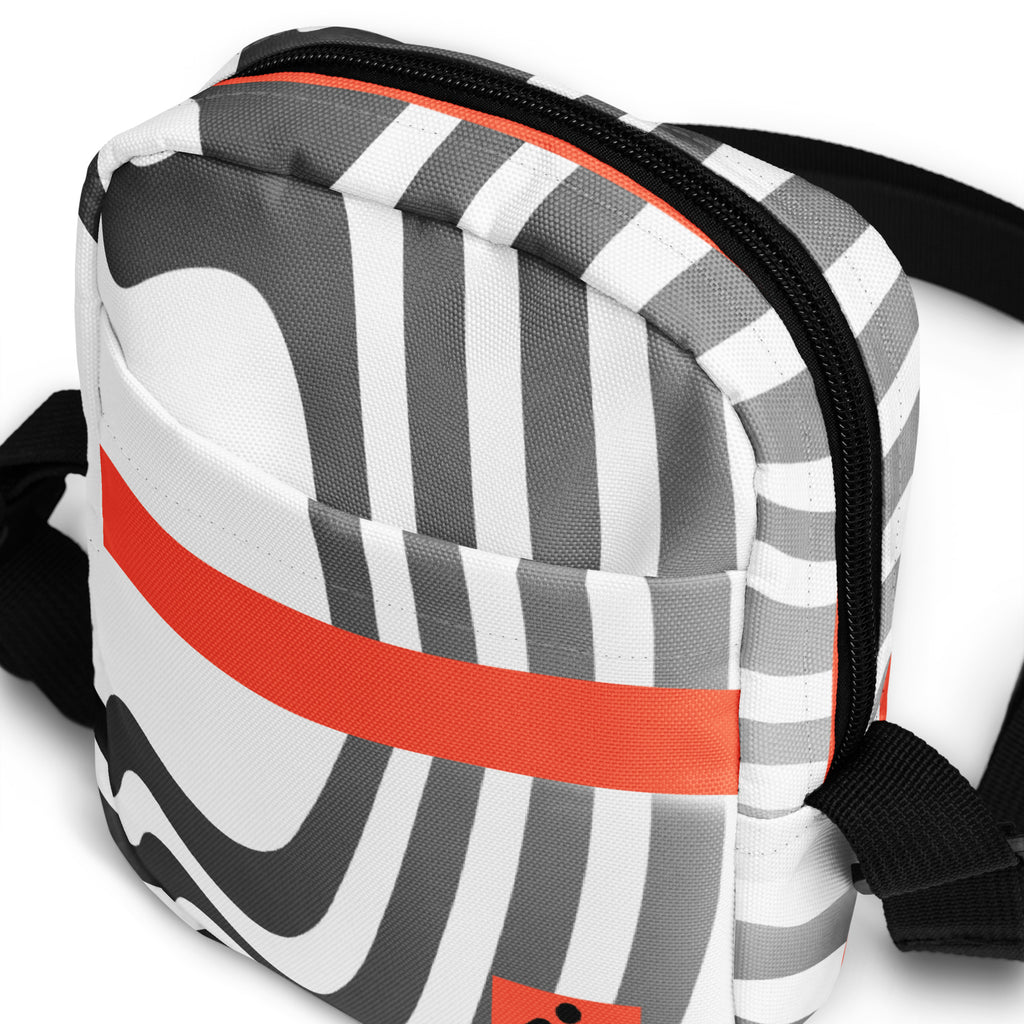 Close-up of the Wrong Turn bag's striped front pocket, horizontal orange band, and black zipper.