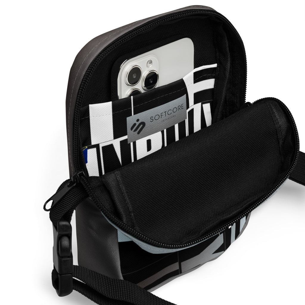 Open Unruly crossbody bag showing a phone in its black-and-white patterned interior pocket.