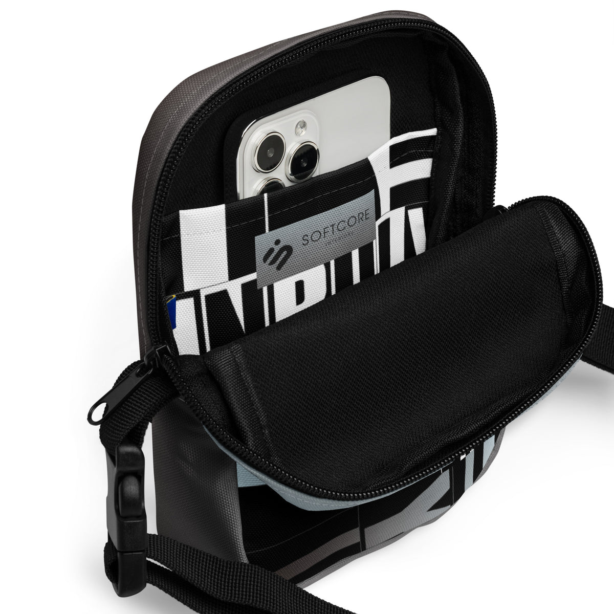 Open Unruly crossbody bag showing a phone in its black-and-white patterned interior pocket.