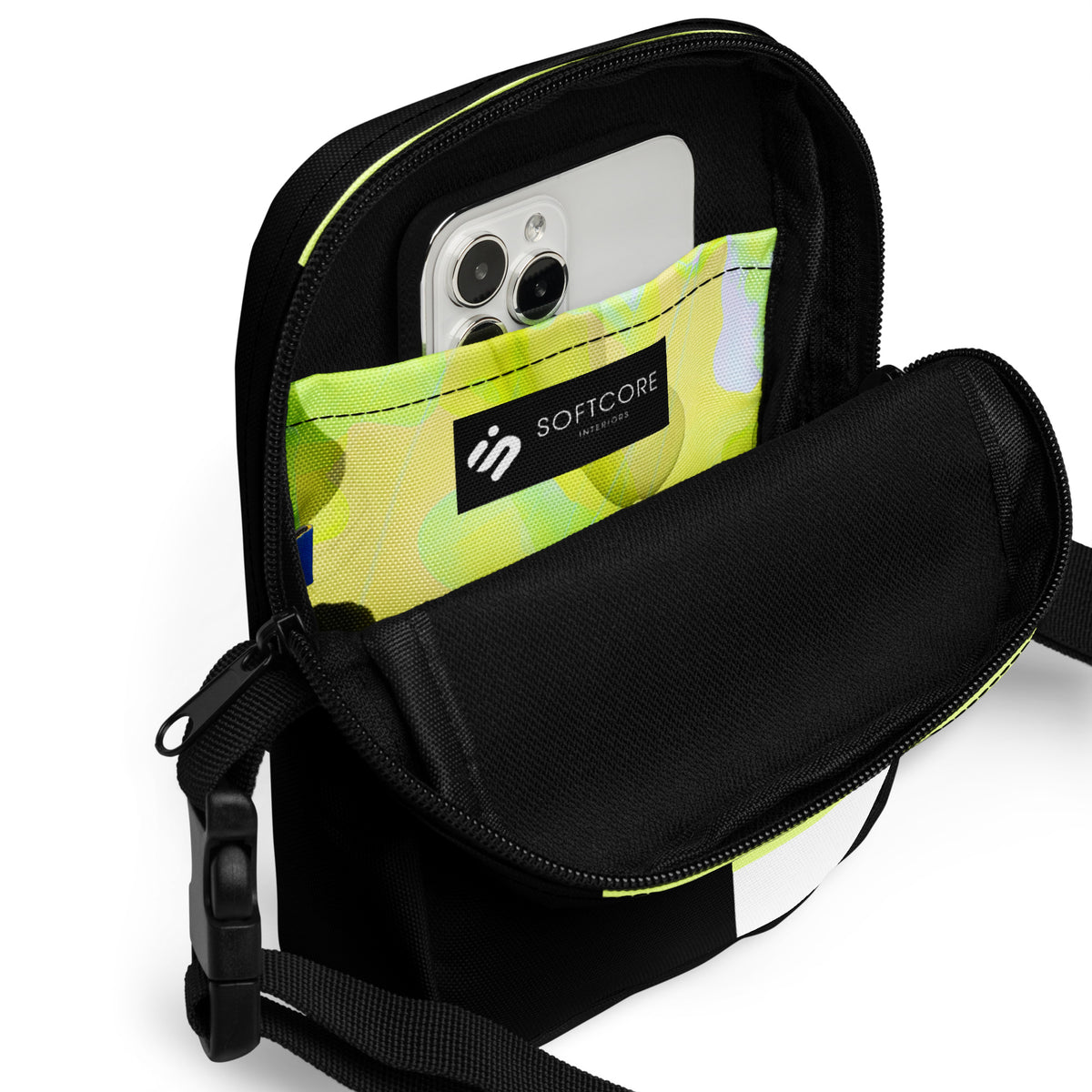 Open Personal Baggage crossbody bag showing a phone in its bright yellow-green patterned interior pocket.