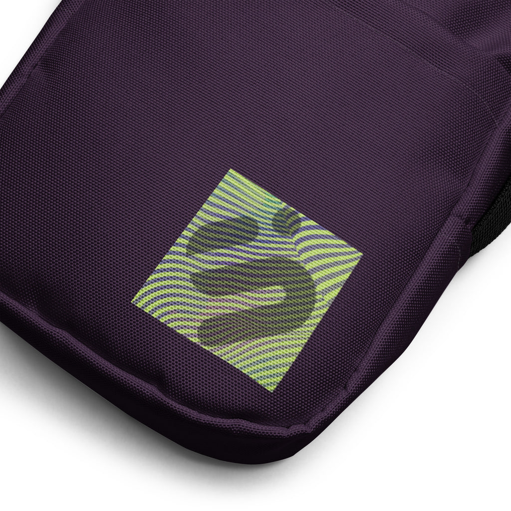 Close-up of the striped yellow-green monogram patch on the purple Velvet Detour bag.