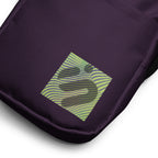Close-up of the striped yellow-green monogram patch on the purple Velvet Detour bag.