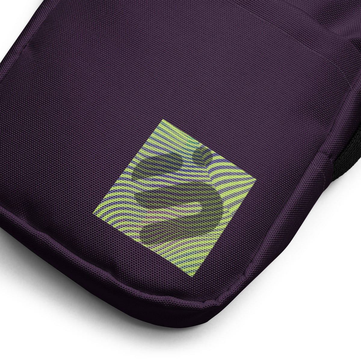 Close-up of the striped yellow-green monogram patch on the purple Velvet Detour bag.