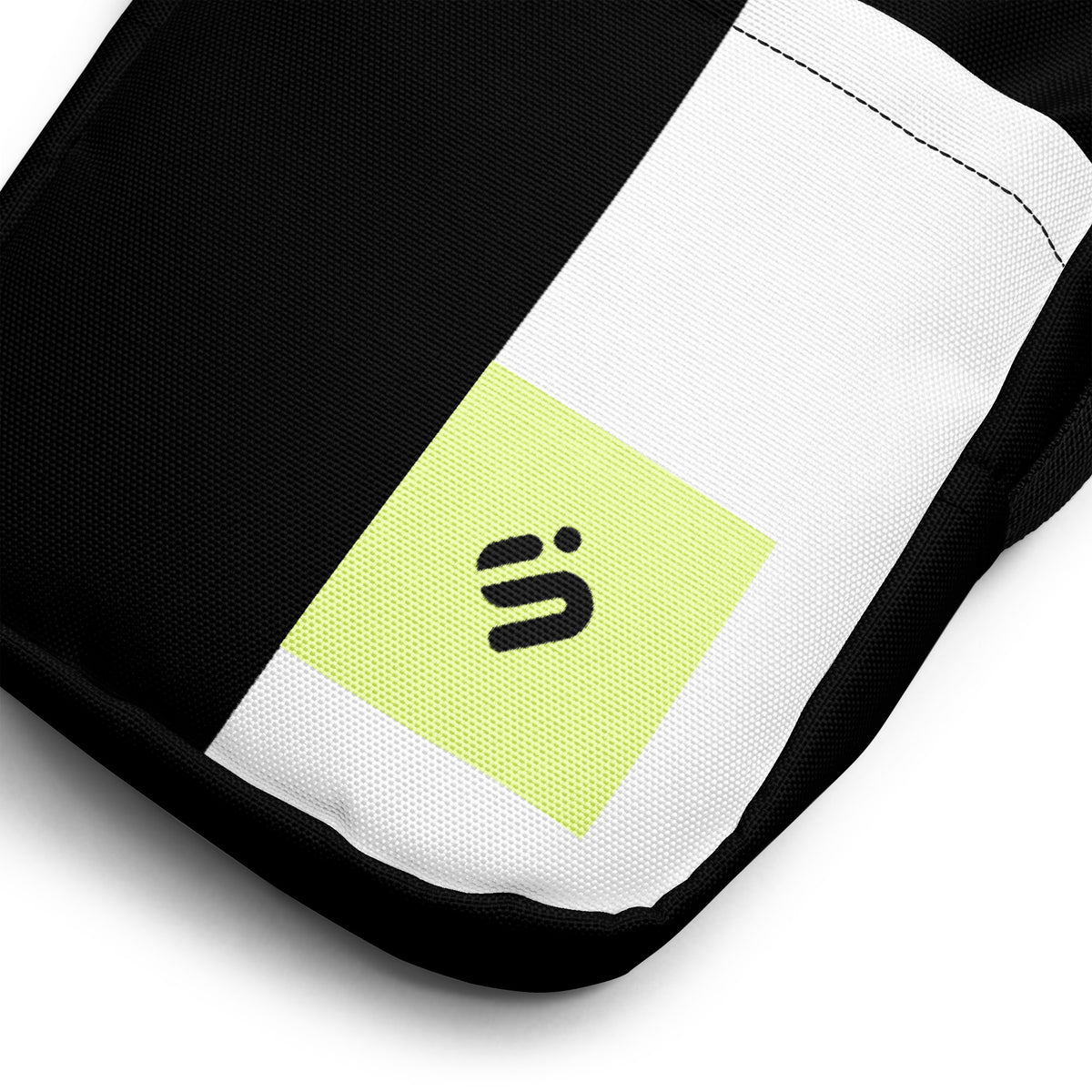 Close-up of the Personal Baggage bag's white stripe and yellow-green monogram patch on black fabric.