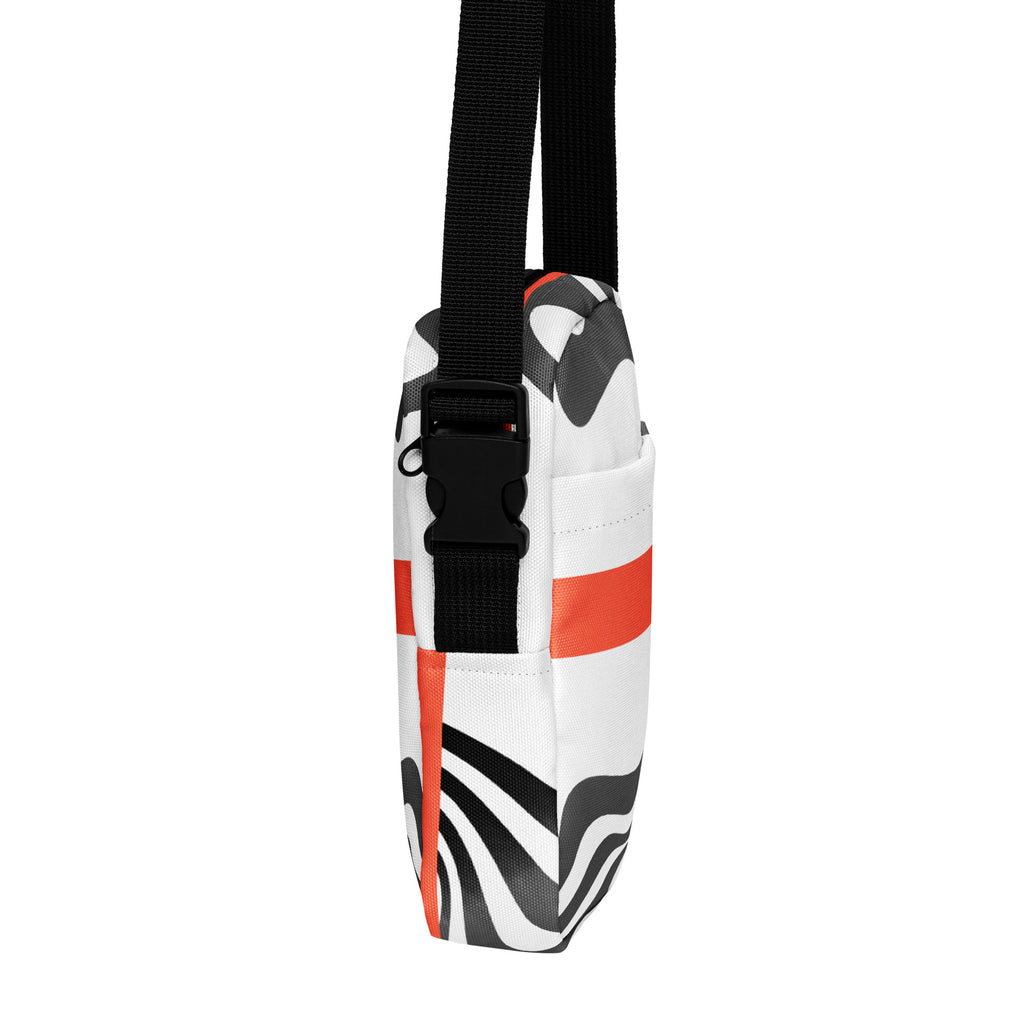 Side view of the Wrong Turn crossbody bag showing its black buckle, wavy stripes, and orange band.