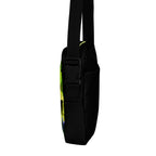 Side view of the Personal Baggage crossbody bag showing a black buckle and a glimpse of its yellow-green patterned back.