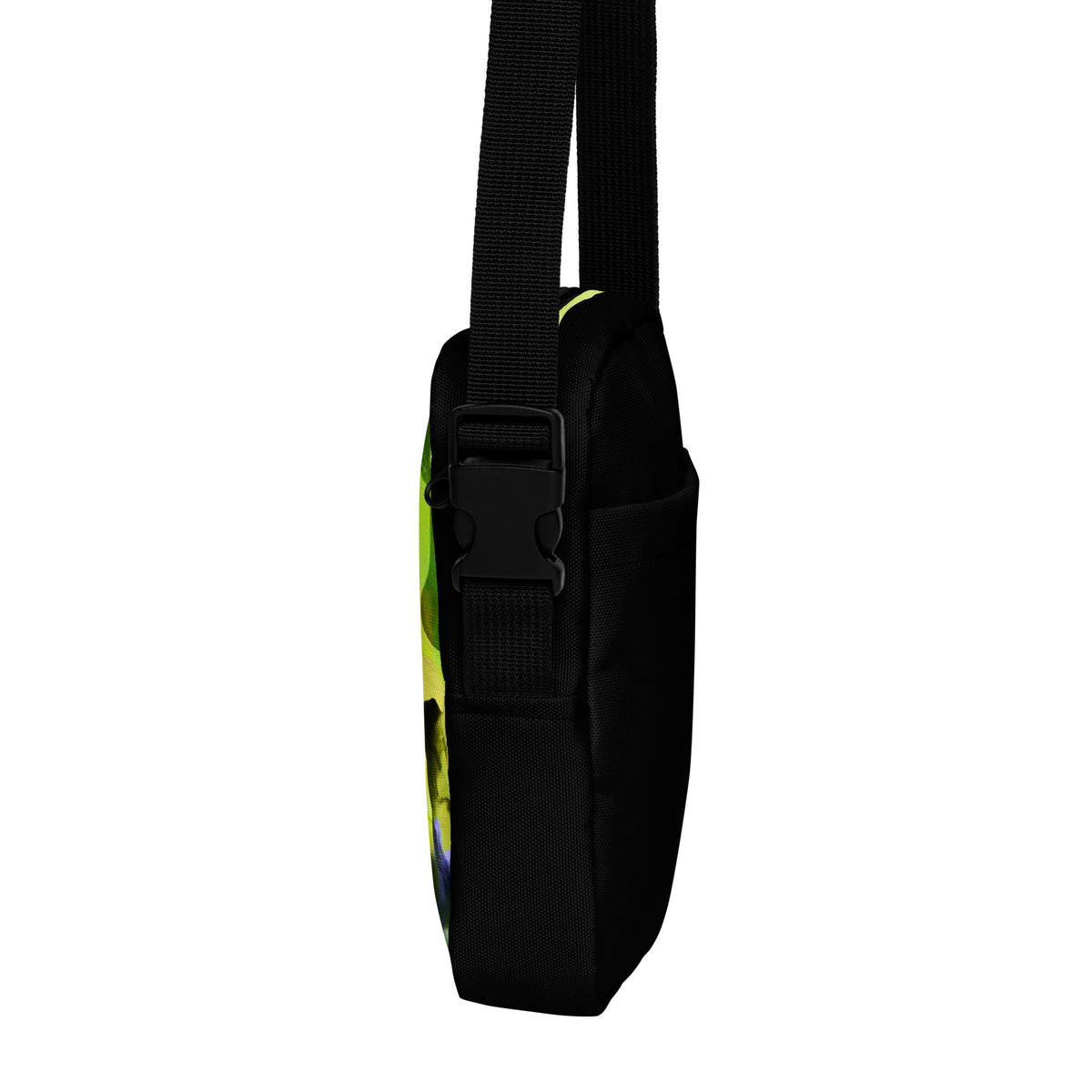 Side view of the Personal Baggage crossbody bag showing a black buckle and a glimpse of its yellow-green patterned back.
