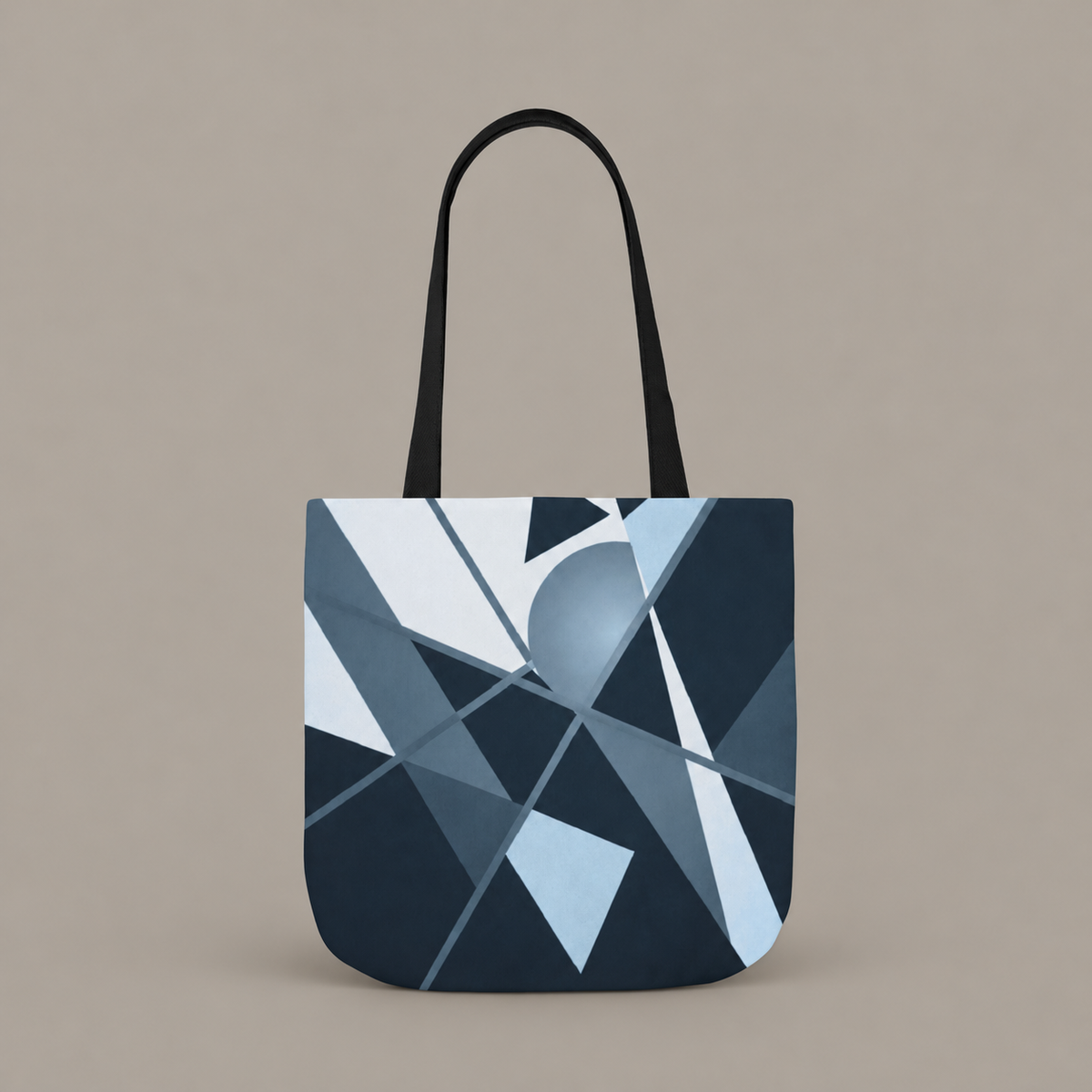 Angles in Transit shoulder tote bag with geometric navy and blue artwork on a warm greige studio background.