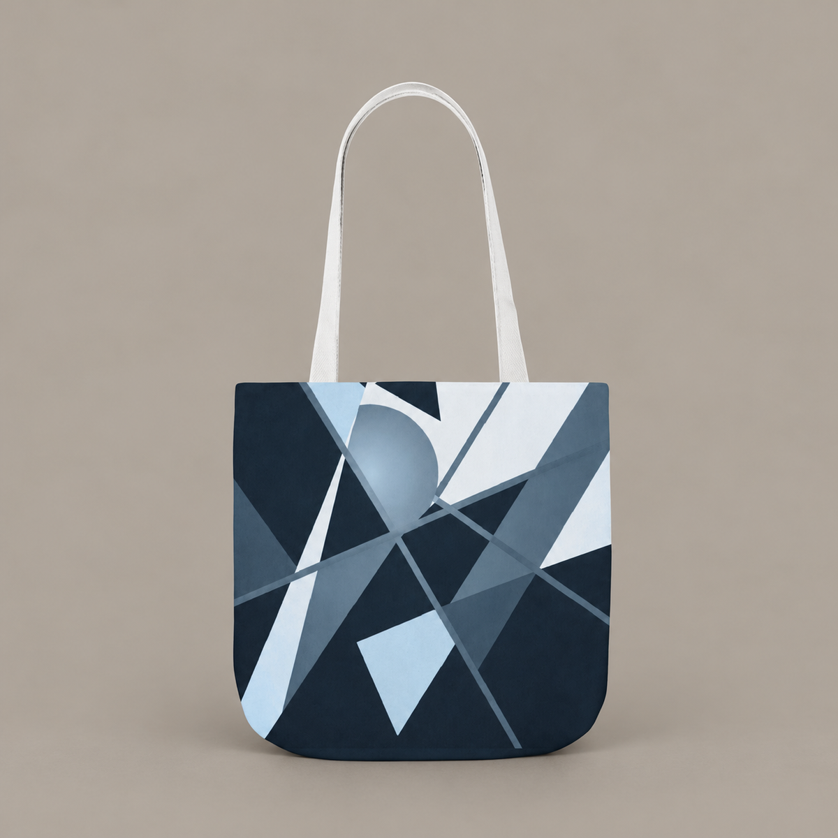 Angles in Transit shoulder tote bag with geometric navy and blue artwork on a warm greige studio background.