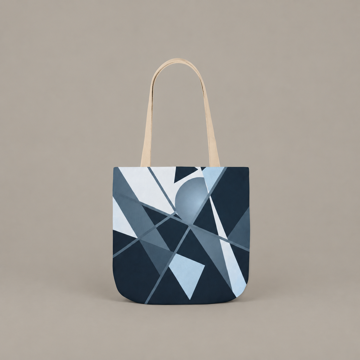 Angles in Transit shoulder tote bag with geometric navy and blue artwork on a warm greige studio background.
