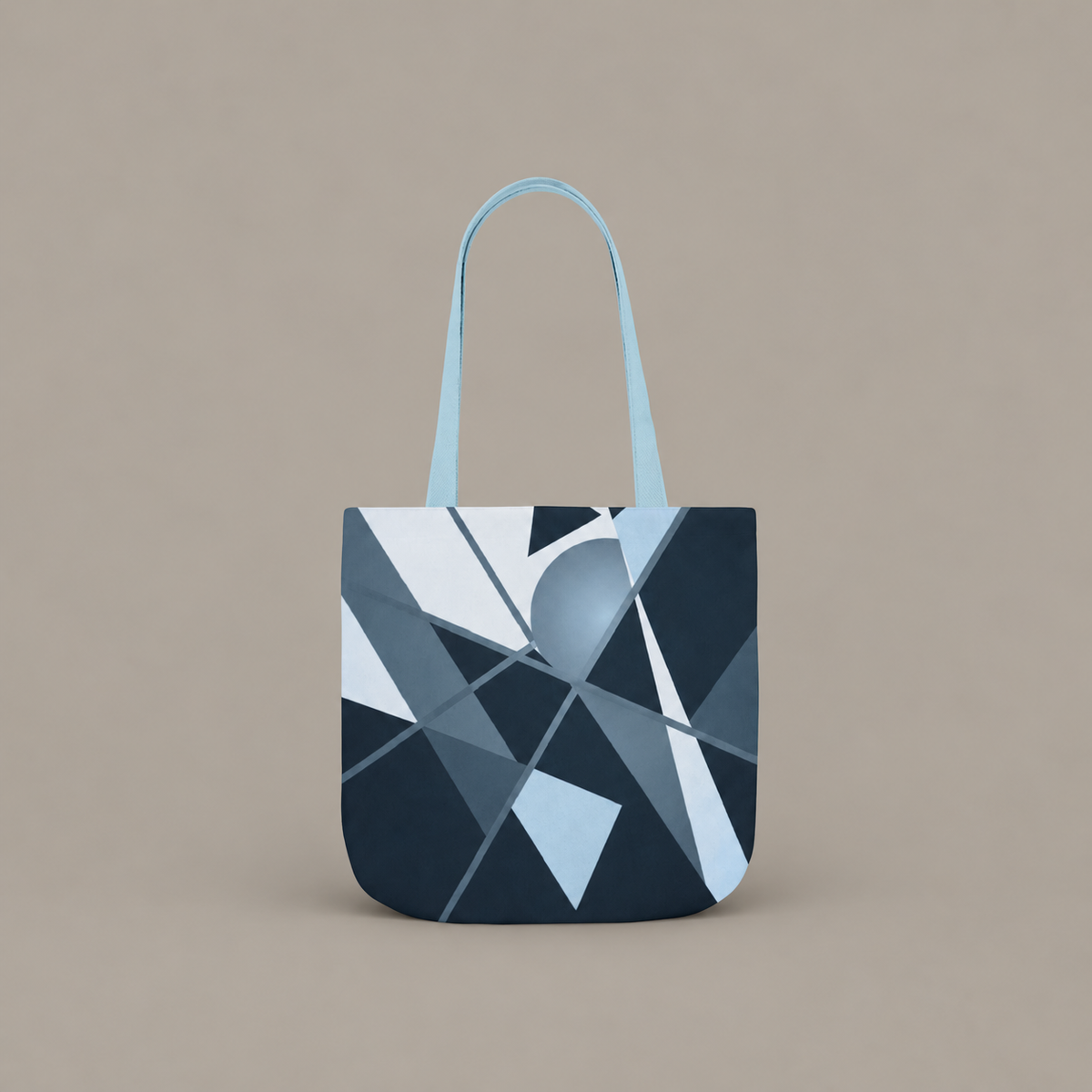 Angles in Transit shoulder tote bag with geometric navy and blue artwork on a warm greige studio background.