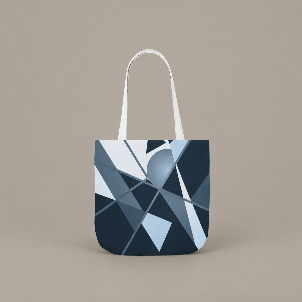 Angles in Transit shoulder tote bag with geometric navy and blue artwork on a warm greige studio background.