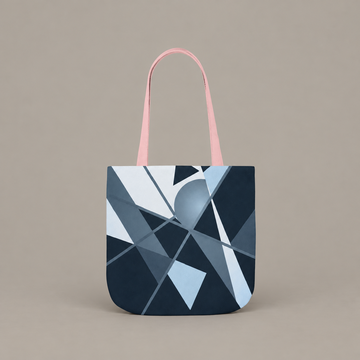 Angles in Transit shoulder tote bag with geometric navy and blue artwork on a warm greige studio background.