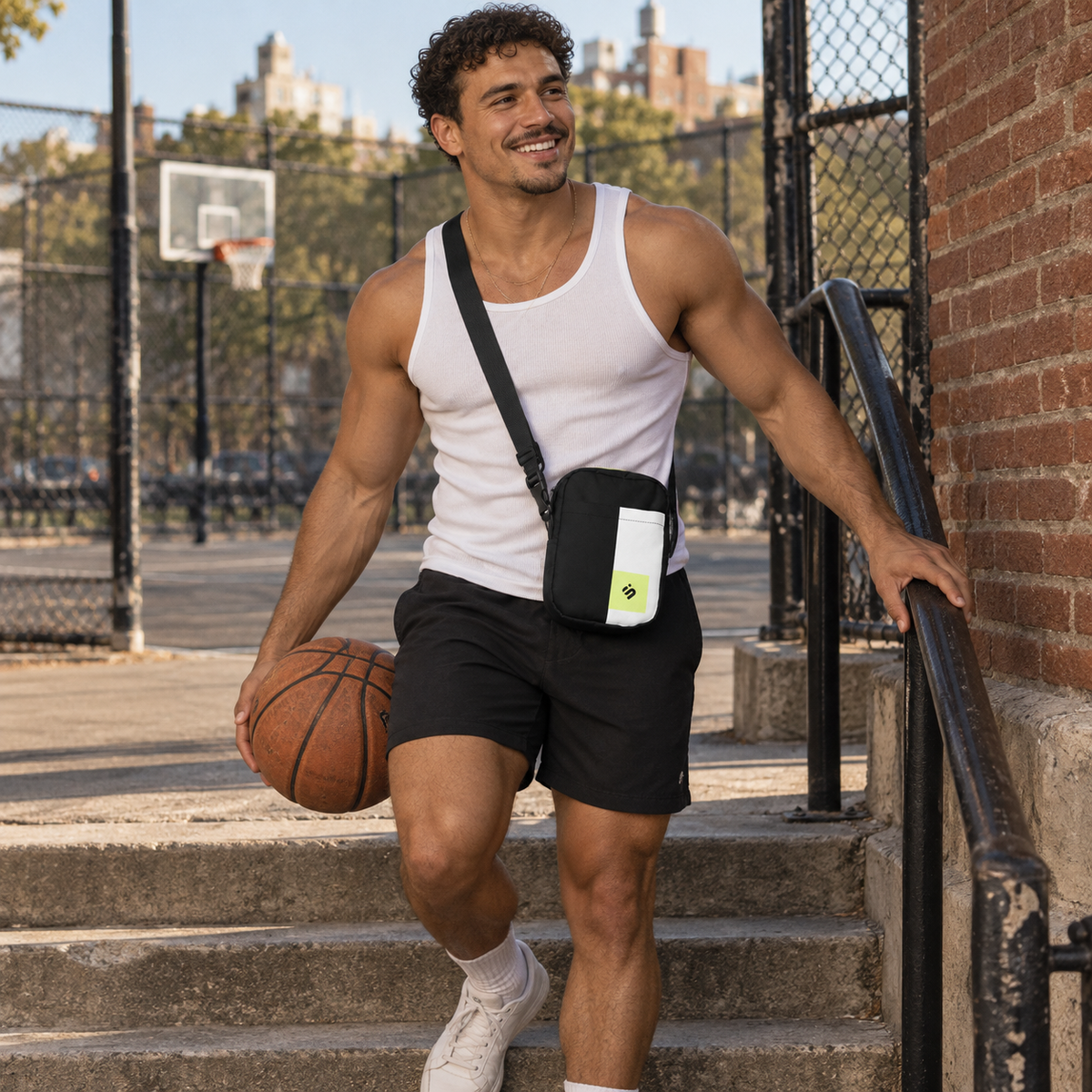 A person holding a basketball beside a court while wearing the Personal Baggage crossbody bag.