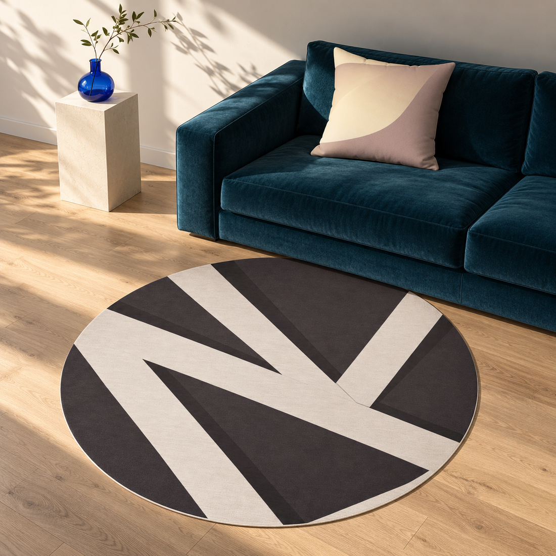 Quite Cut circular rug and Subtle Seduction cream-and-taupe pillow in a sunlit room with a petrol sofa and blue vase.