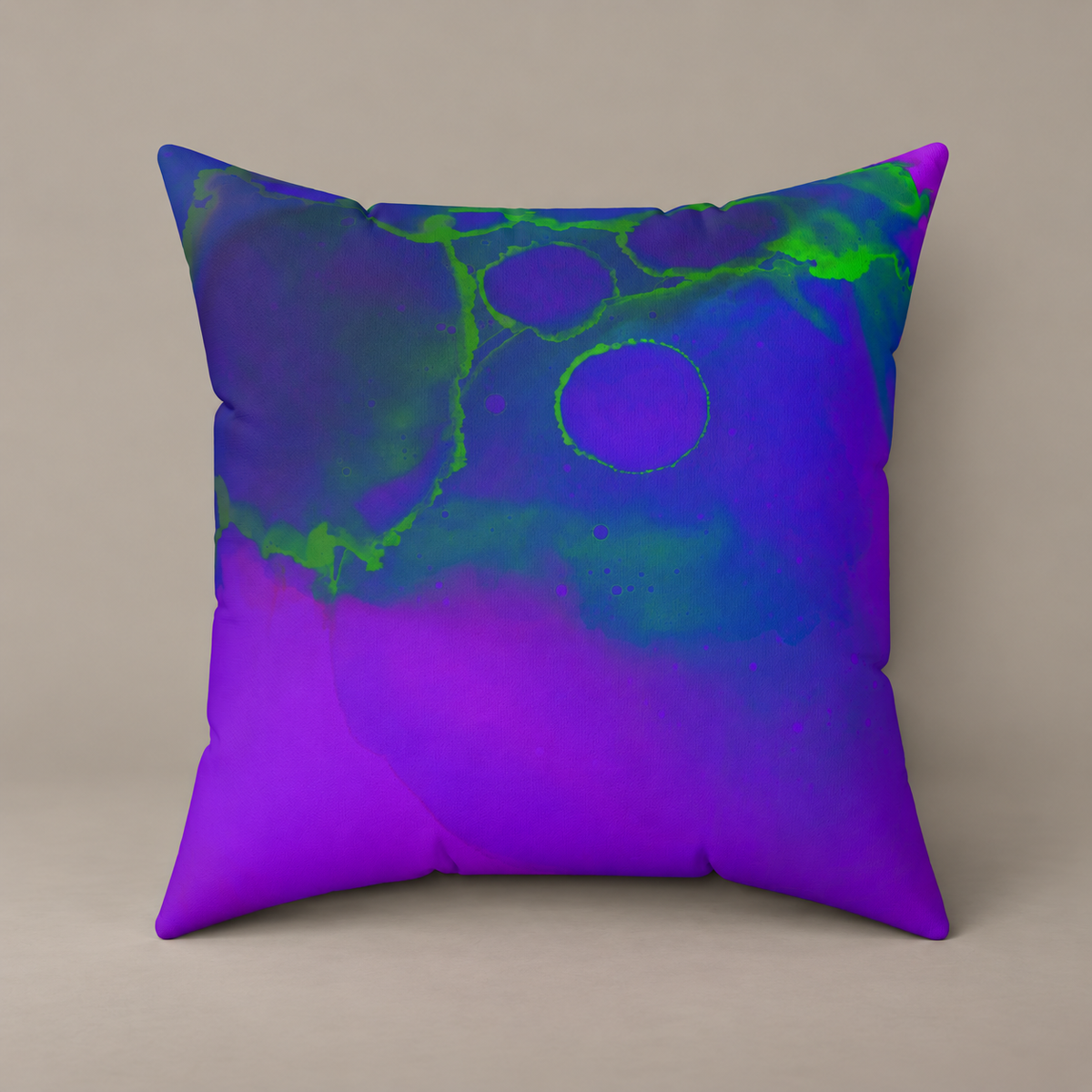 Toxic Glow-Up faux-suede pillow with blue, violet and vivid green abstract artwork on a warm greige studio surface.