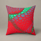 Venomous Kiss faux-suede pillow with red, teal and green scale-like artwork on a warm greige studio surface.